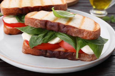 Nefis Caprese sandviçleri, mozarella, domates ve fesleğen, ahşap masa, yakın plan.