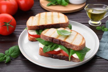 Nefis Caprese sandviçleri, mozarella, domates ve ahşap masada fesleğen.