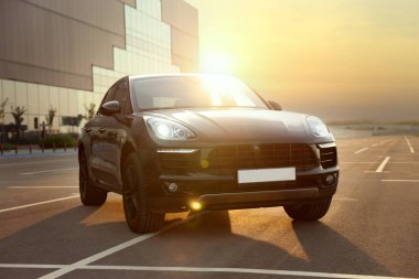 Gündoğumunda park yerinde park edilmiş modern siyah araba.