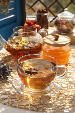 Aromatik çay, farklı kuru bitkiler ve beyaz masada bal.