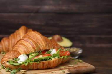 Somon, avokado, mozzarella ve marul ile ahşap masada lezzetli kruvasan, yakın plan. Metin için boşluk