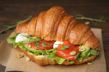 Somon, avokado, mozzarella ve marul ile ahşap masada lezzetli kruvasan, yakın plan.