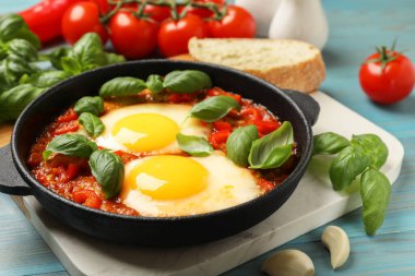Lezzetli Shakshuka, açık mavi ahşap masada servis yapıyor, yakın plan.
