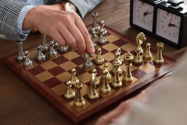 Men playing chess during tournament at wooden table, closeup