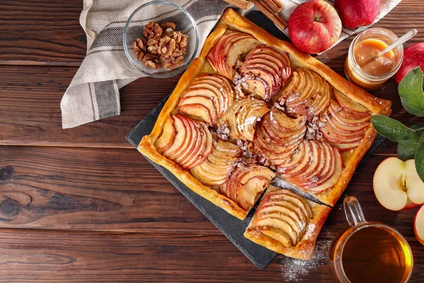Freshly baked apple pie served with tea on wooden table, flat lay. Space for text