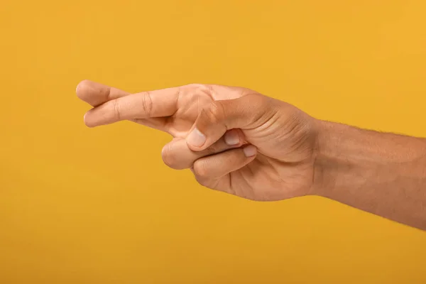 Man crossing his fingers on orange background, closeup