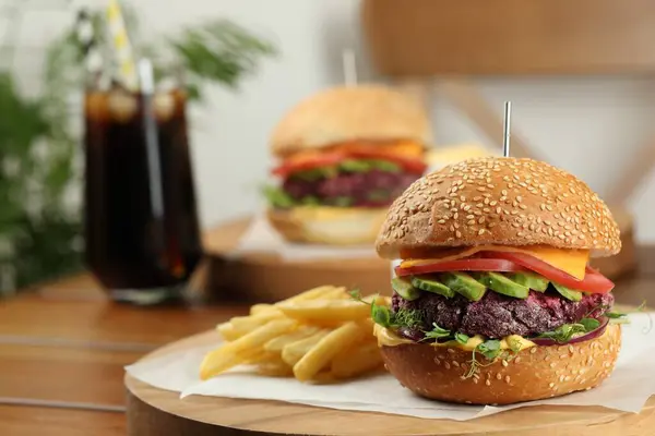 Tasty vegetarian burger served with french fries on wooden table, closeup. Space for text