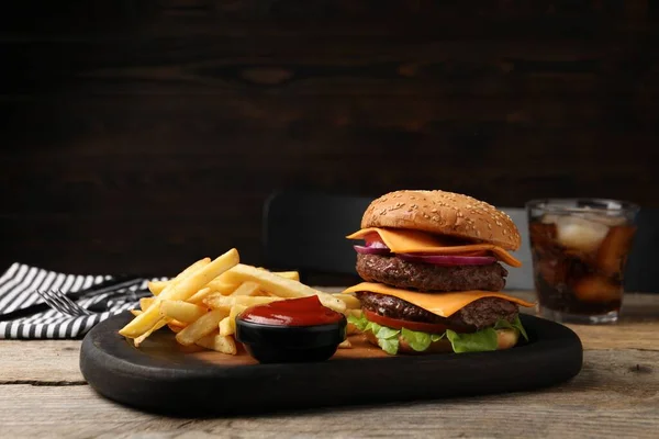 Delicious burger with meat cutlets, french fries and sauce on wooden table