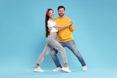 Mutlu çift açık mavi arka planda dans ediyor.