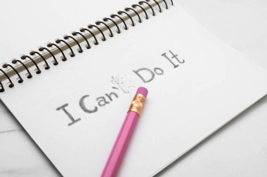 Motivasyon konsepti. I Can 't Do It' ten I Can 't Do It' e, beyaz masadaki T harfini silerek değiştirilmiş bir defter.