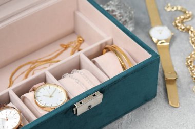 Açık gri masada birçok farklı aksesuar bulunan mücevher kutusu, yakın plan.