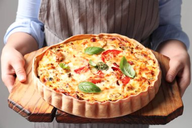 Gri arkaplanda lezzetli kiş taşıyan kadın, yakın plan.