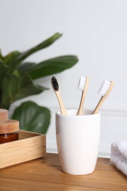 Bambu diş fırçaları tutacakta, havluda, kozmetik ürünlerde ve ahşap masadaki yapraklarda