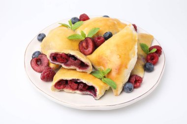 Beyaz üzerine izole edilmiş nane yaprakları ve böğürtlenli lezzetli samosalar.