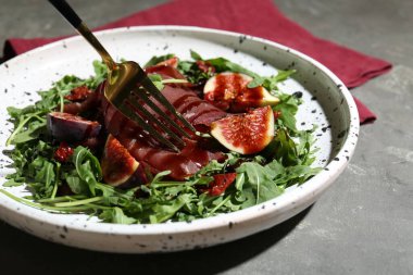 Gri masadaki çatallı lezzetli bresaola salatası, yakın plan.