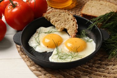 Lezzetli kızarmış yumurtalar, beyaz ahşap masada ekmek ile servis edilir, yakın plan.