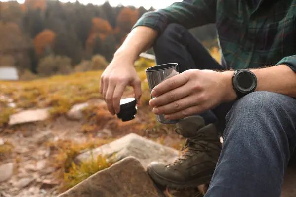 Man with thermo tumbler in nature, closeup. Space for text