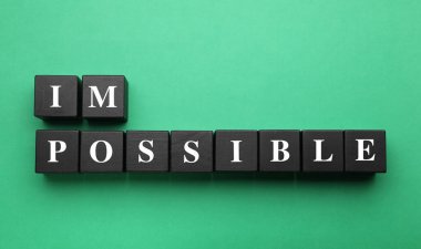 Motivasyon konsepti. Yeşil arkaplandaki siyah tahta küpleri kaldırarak sözcüğü imkansızdan olanaksıza çevirmek, düz yatıyordu