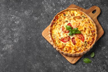 Lezzetli kiş, domates, fesleğen ve peynir, koyu dokulu masa, üst manzara. Metin için boşluk