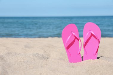 Plaj kumlarında pembe parmak arası terlikler, metin için yer