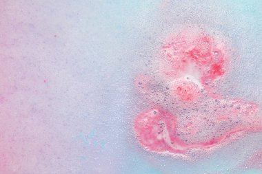 Sudaki banyo bombasını çözdükten sonra renkli köpük, yakın plan.