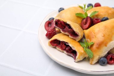 Lezzetli samosa tabağı, beyaz fayanslı masa üzerinde çilek ve nane yaprakları, yakından. Metin için boşluk