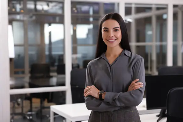 Smiling woman with crossed arms in office, space for text. Lawyer, businesswoman, accountant or manager