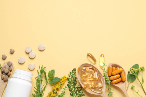 Different pills, herbs and flowers on light yellow background, flat lay with space for text. Dietary supplements
