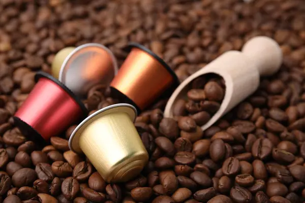 Many different coffee capsules and scoop on beans, closeup