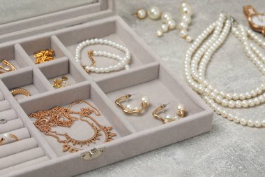 Açık gri masada birçok farklı aksesuar bulunan mücevher kutusu, yakın plan.