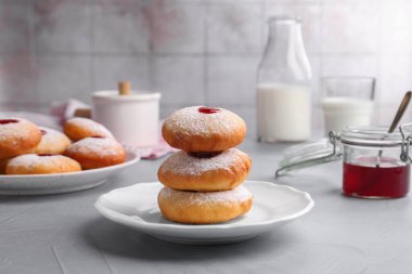 Açık gri masada servis edilen pudra şekerli jöleli Hanuka çörekleri.