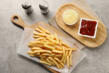 Gri masadaki soslarla servis edilen lezzetli patates kızartması.