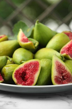 Beyaz mermer masa üzerindeki tüm yeşil incirlerle bulanık arka plan, yakın plan