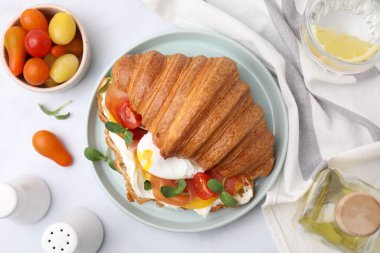 Lezzetli kruvasan, sahanda yumurta, domates ve mikroyeşillikler beyaz masada servis ediliyor.