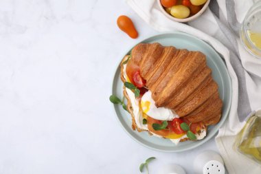 Lezzetli kruvasan, sahanda yumurta, domates ve mikroyeşillikler beyaz masada servis ediliyor. Metin için boşluk