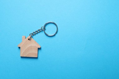 Açık mavi arka planda, ev şeklinde ahşap anahtarlık, üst manzara. Metin için boşluk