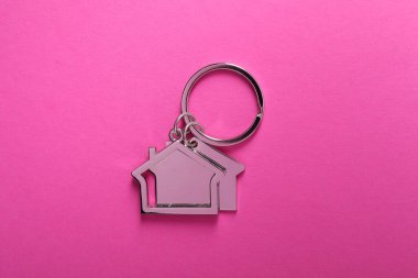 Parlak pembe arka planda ev şeklinde metal anahtarlıklar, üst görünüm