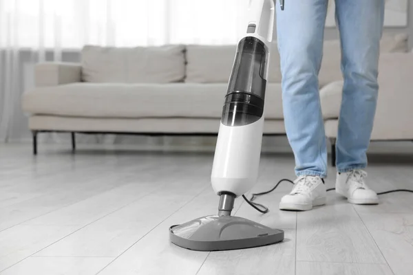 Man cleaning floor with steam mop at home, closeup. Space for text