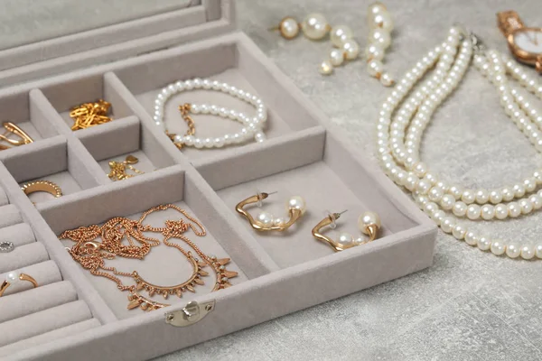 Jewelry box with many different accessories on light grey table, closeup