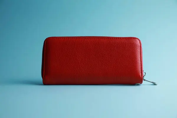 One stylish leather purse on light blue background