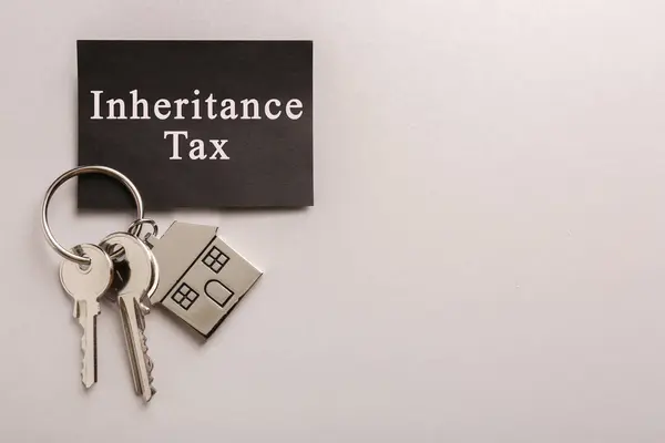 Card with phrase Inheritance Tax and keys with house shaped key chain on grey background, top view. Space for text