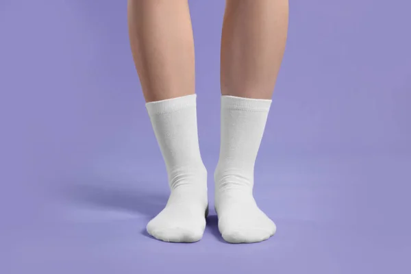 Woman in stylish white socks on violet background, closeup