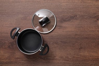 Boş siyah tencere ve cam kapak ahşap masa, düz yatıyordu. Metin için boşluk