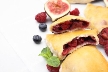 Lezzetli samosalar, böğürtlenler, nane yaprakları ve beyaz fayanslı masa üzerinde incir, yakın plan. Metin için boşluk