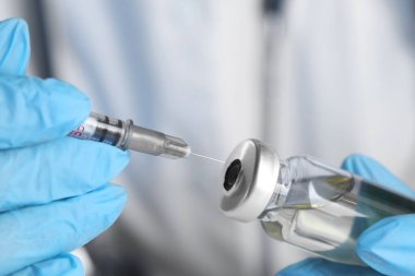 Doktor cam şişeye şırınga yerleştiriyor.