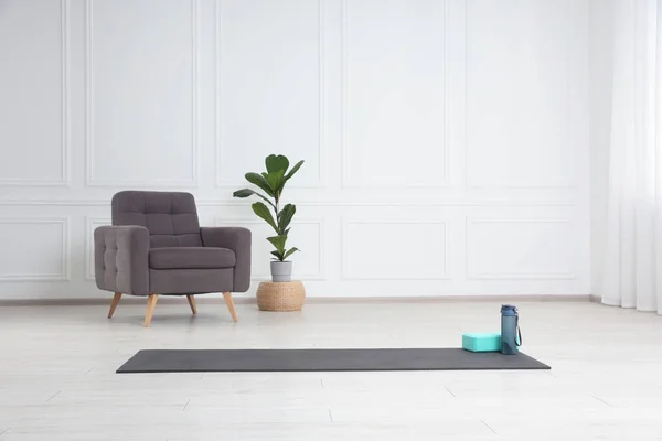 Exercise mat, yoga block and bottle indoors. Space for text