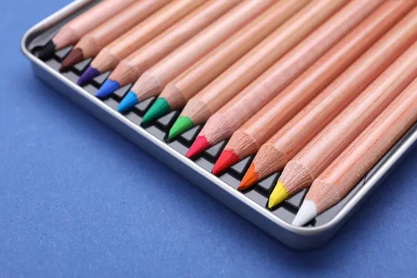 Colorful pastel pencils in box on blue background, closeup. Drawing supplies