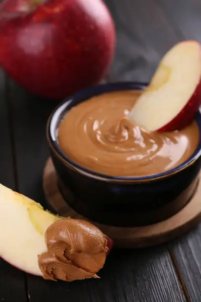 Slices of fresh apple with peanut butter on wooden table, closeup