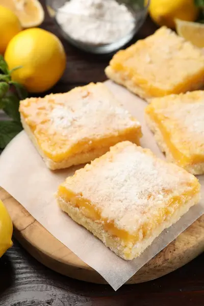 Tasty lemon bars with powdered sugar on table, closeup