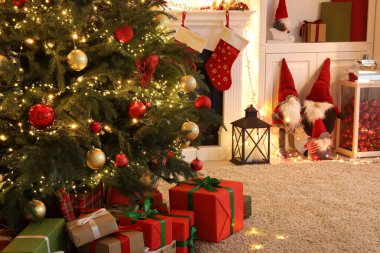 Oturma odasının içinde şömine ve şenlikli dekor var. Noel kutlaması